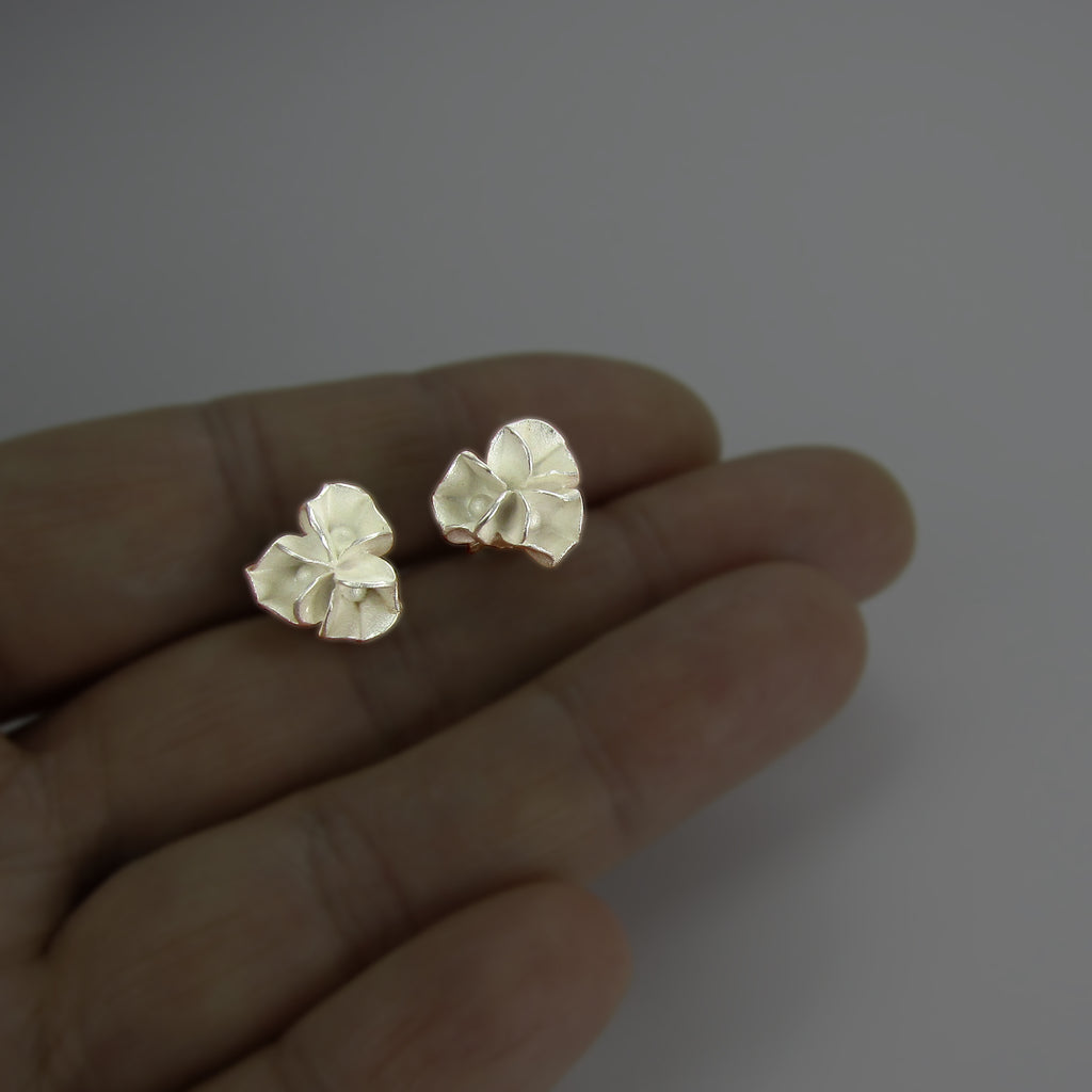 Ohrstecker aus Silber in Blütenform auf der Hand liegend